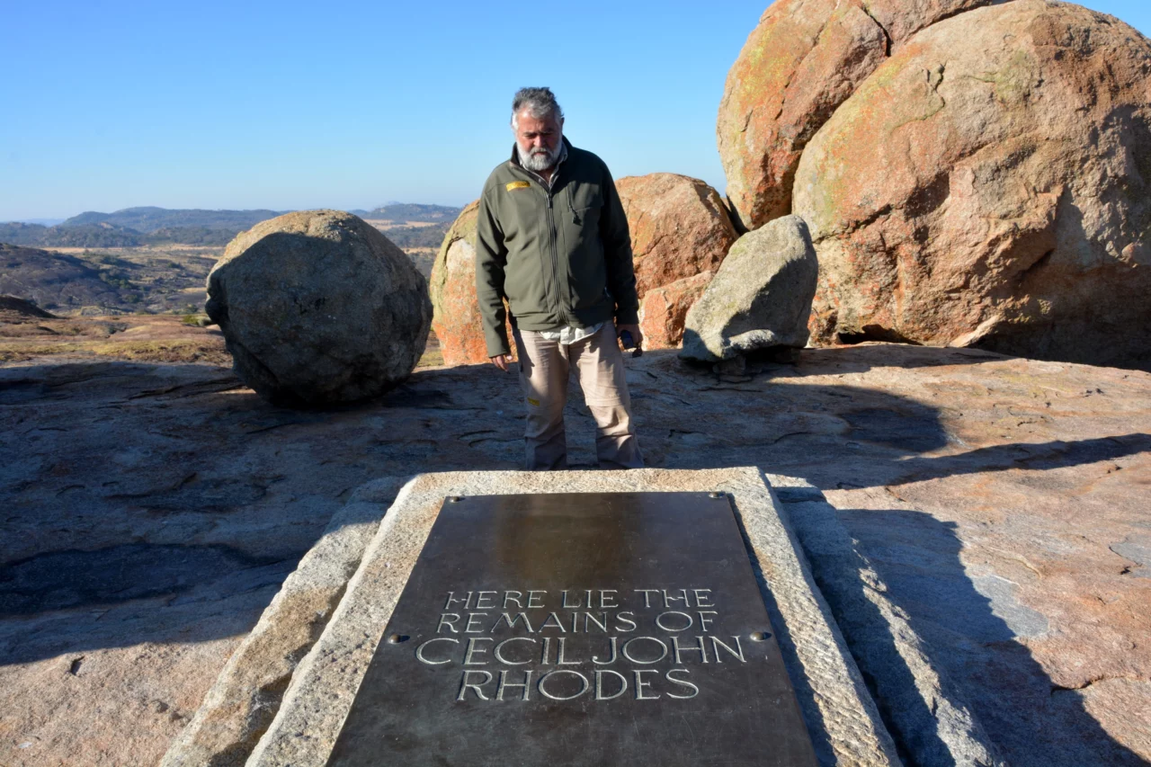 Photo of Johan Badenhorst in front of the grave of Cecil John Rhode. This image shows Johand Badenhorst staring at the grave with a scenic background showcasing the amazing view of Matabeleland. This was taken during the Voetsporerentals trip exploring Matabeleland. 
