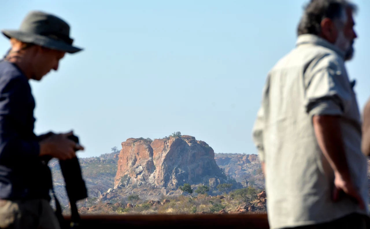 Scenic photo of a rocky mountain in Matabeleland. Photo showcases a beautiful rocky mountain in the backround with 2 members of the Voetspore team in the foreground. This image was taken during the amazing camping trip of Voetsporerentals to explore Matabeleland. 
