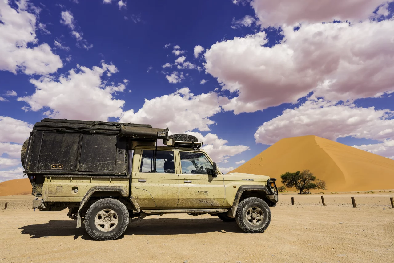 Explore Namibia feature image showcasing the voetspore overlanding landcruiser in the Namibia desert with a beautiful sand dune behind it.